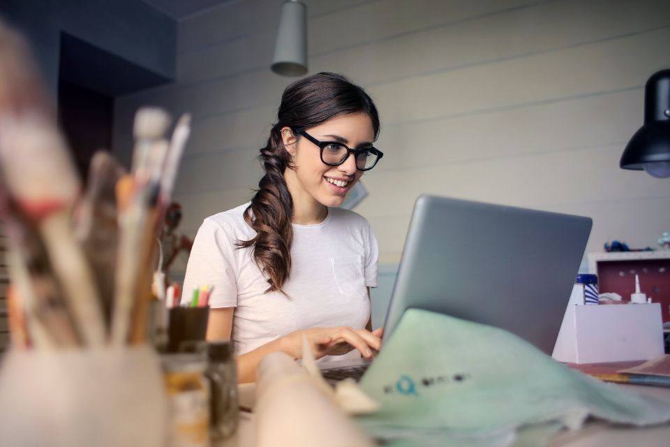 Lachende vrouw met een bril achter een laptop