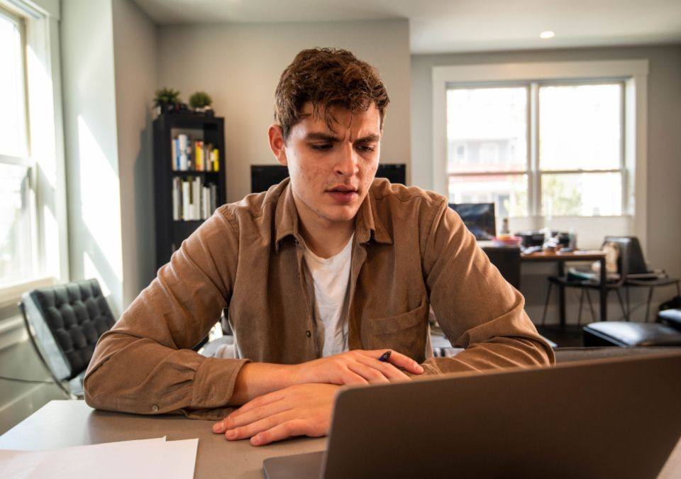 Jonge man werkt thuis achter een laptop